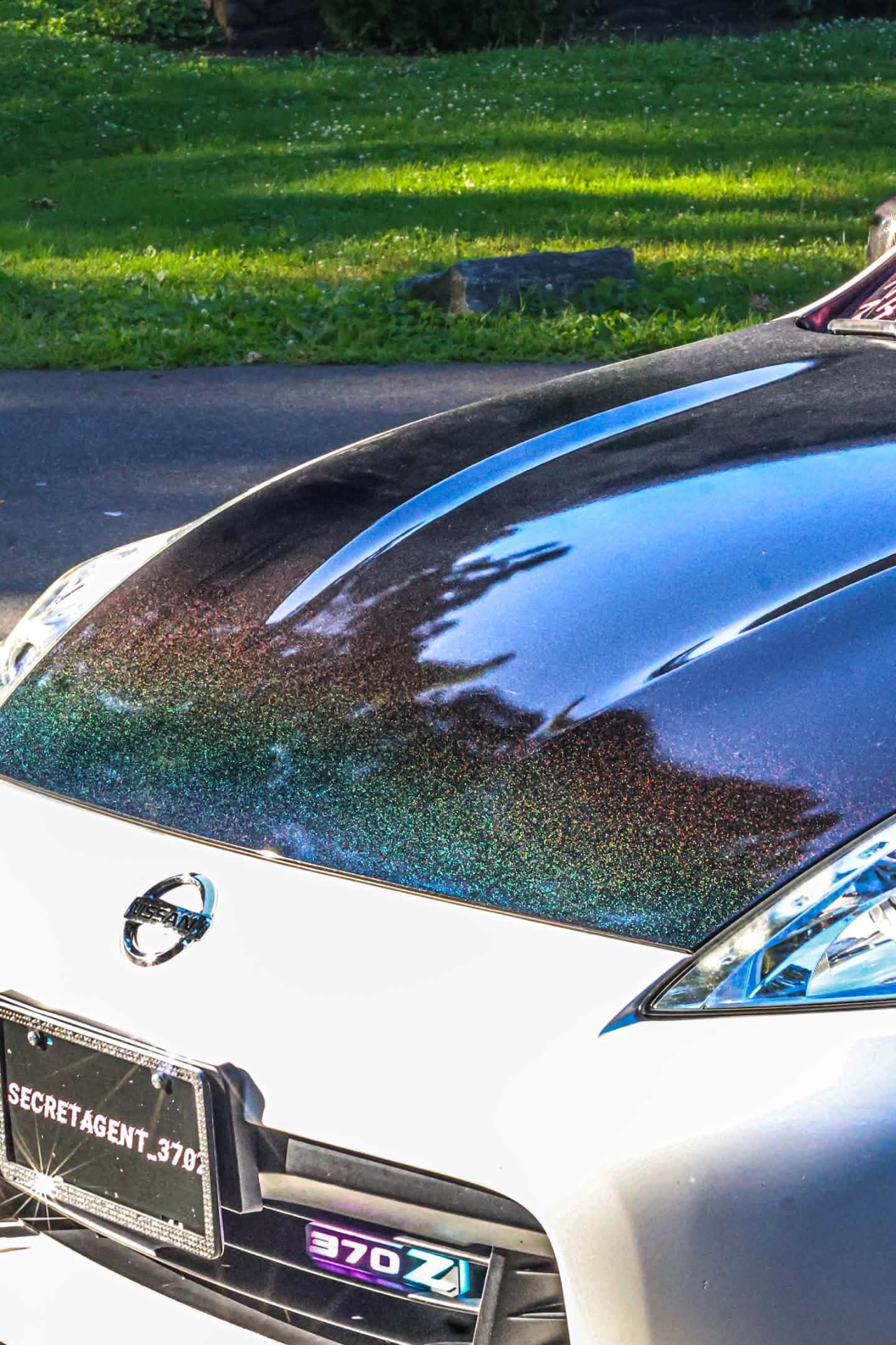 Close-up of the carbon-fiber hood on the 370Z shimmering with rainbow holographic flake in low sun.