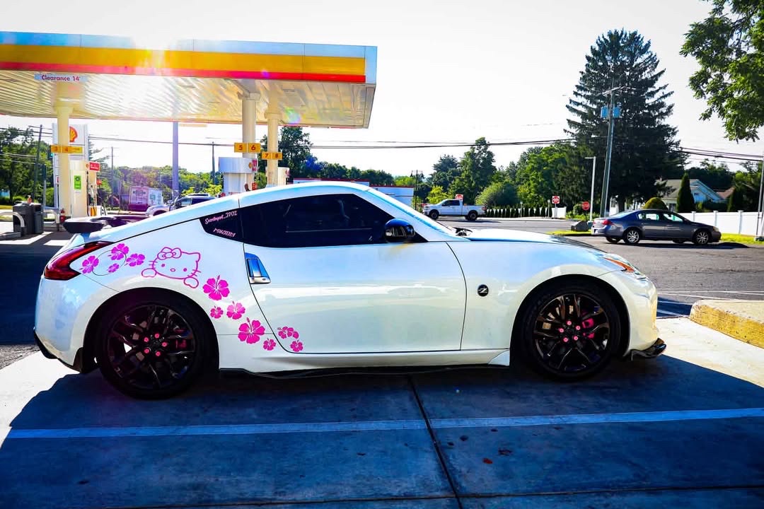 Side profile of the 370Z at a Shell gas station, pink Hello Kitty and hibiscus decals across the door.